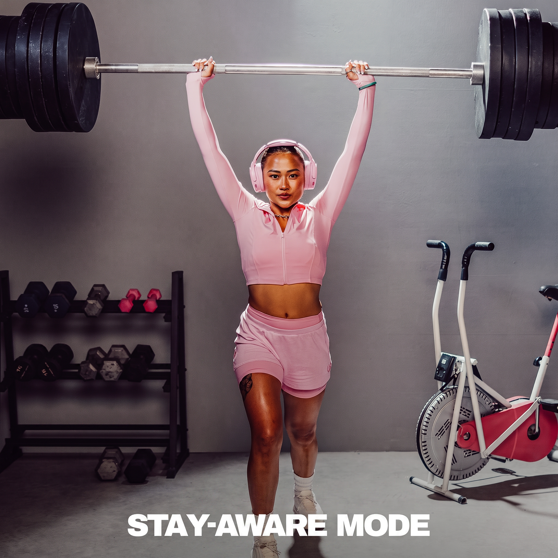 Person with Crusher 1080 ANC Headphones lifting a barbell with gym equipment in the background | Candy