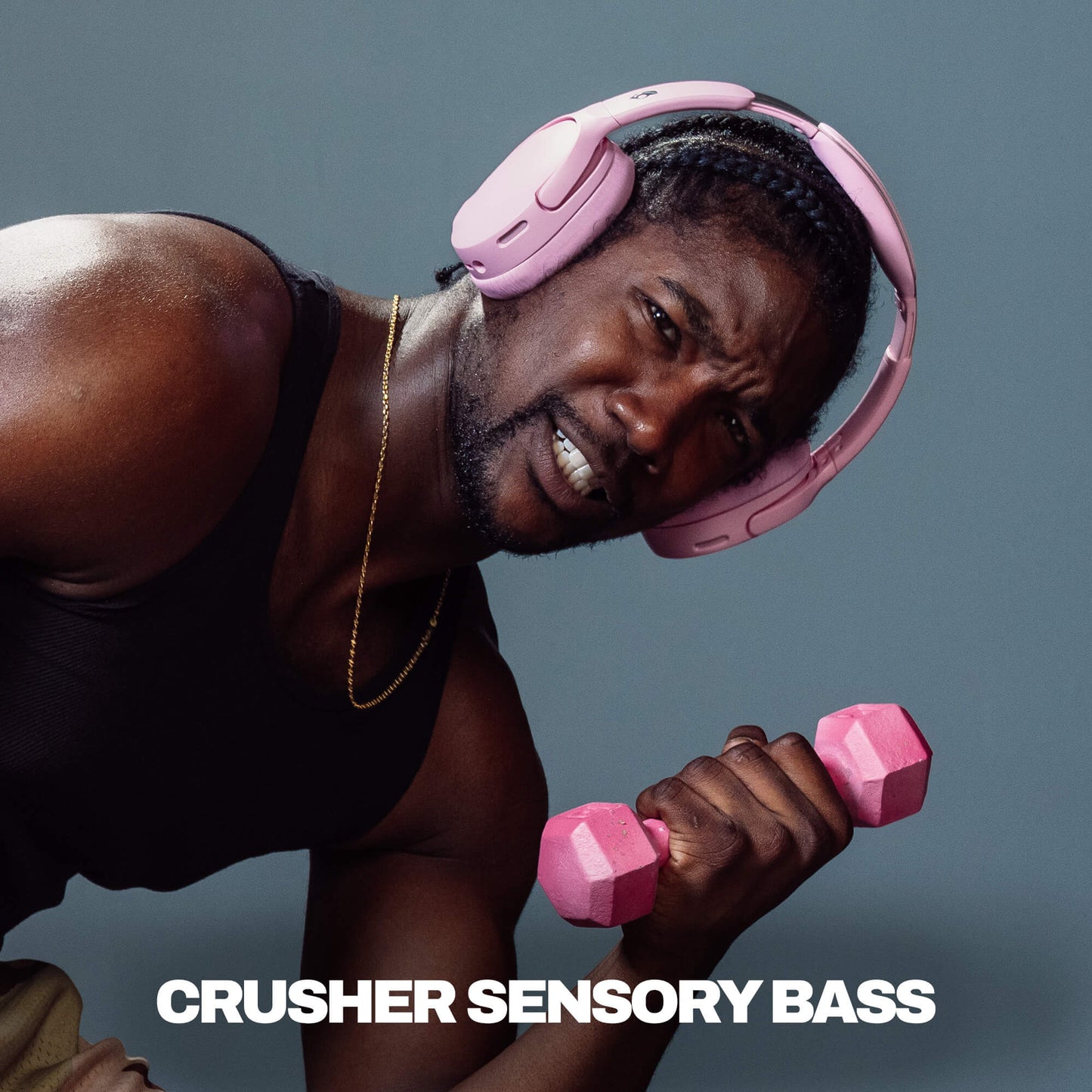 Man wearing pink headphones and holding pink dumbbells with text 'CRUSHER SENSORY BASS' on a gray background | Candy