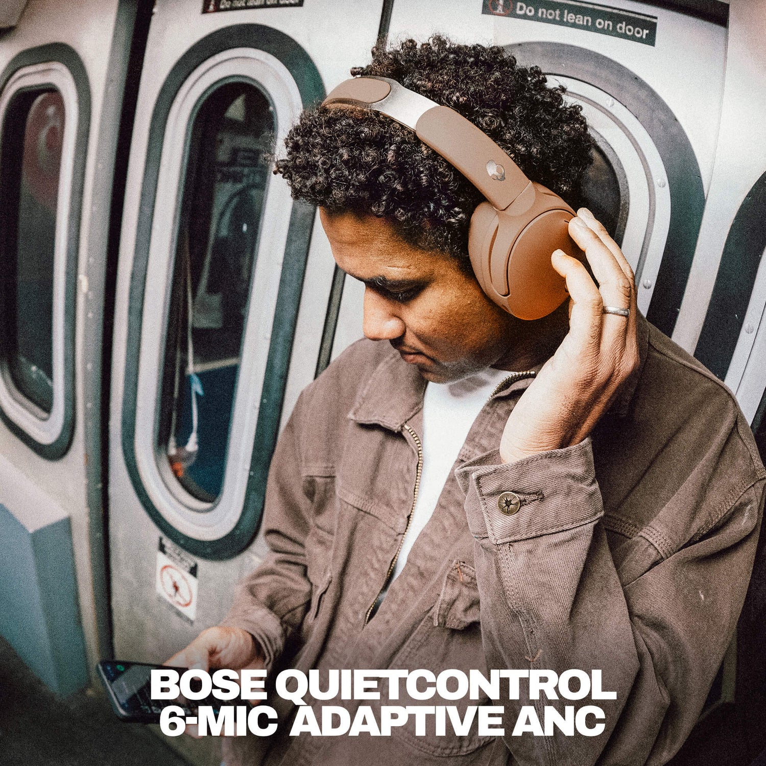 Person wearing Skullcandy crusher 1080 ANC with Bose QuietControl headphones on a subway train, with product name displayed. | Primer
