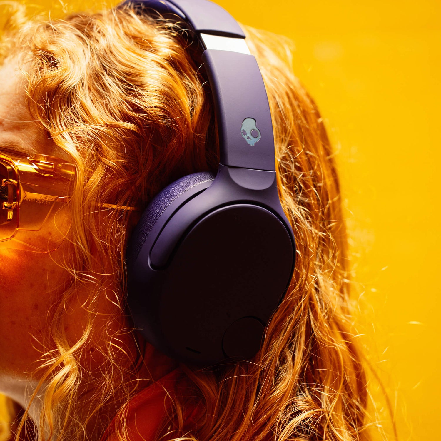 Person wearing purple Crusher 720 headphones with a skull logo on a bright yellow background | Future