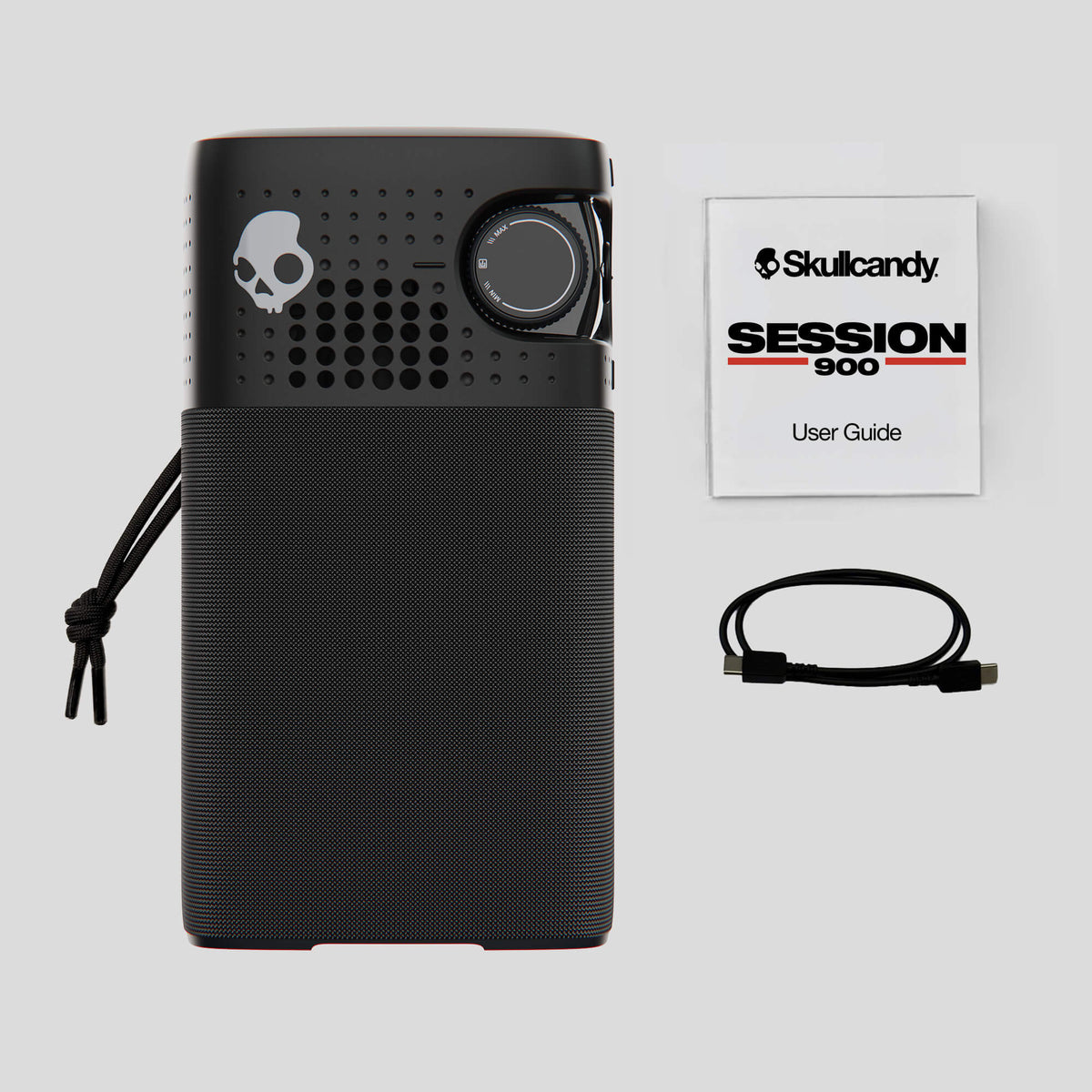 A black Skullcandy Session 900 portable speaker shown with its user guide booklet, charging cable, and carrying strap on a light gray background. | True Black