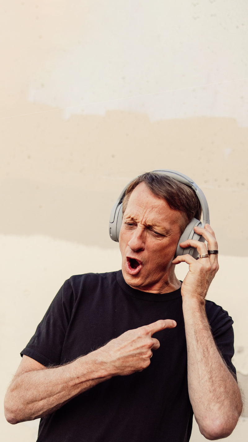 Man wearing headphones and pointing to his ear in a desert setting