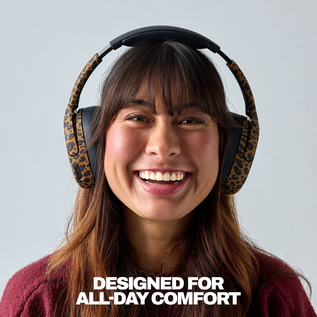 A smiling woman wearing leopard-print over-ear headphones against a light gray background, with the text 'DESIGNED FOR ALL-DAY COMFORT' at the bottom. | Leopard