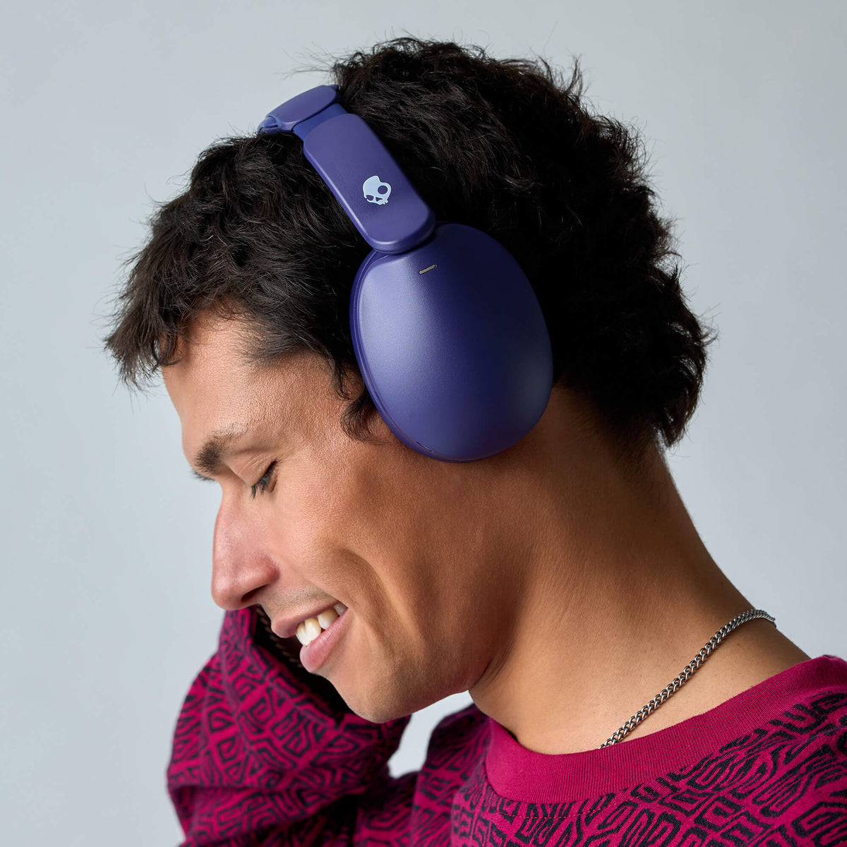 A man wearing a pair of matte purple hesh 360 over-ear headphones and a magenta patterned shirt, shown in profile against a light gray background. | Future
