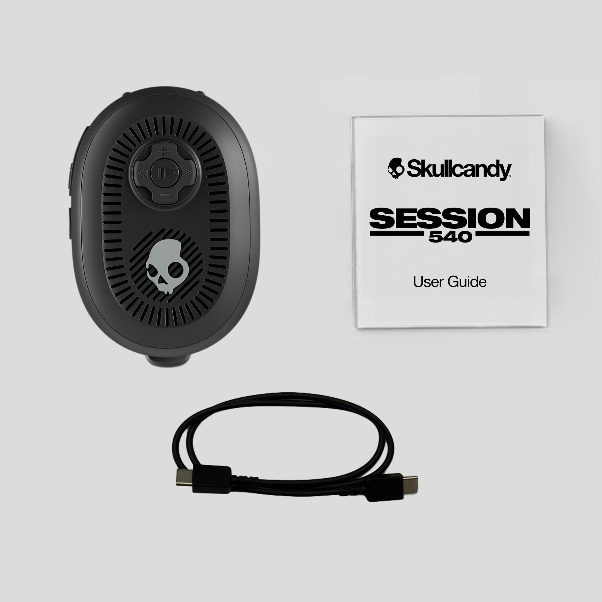 Black electronic device with cable and Skullcandy user guide on a light gray background | Plasma
