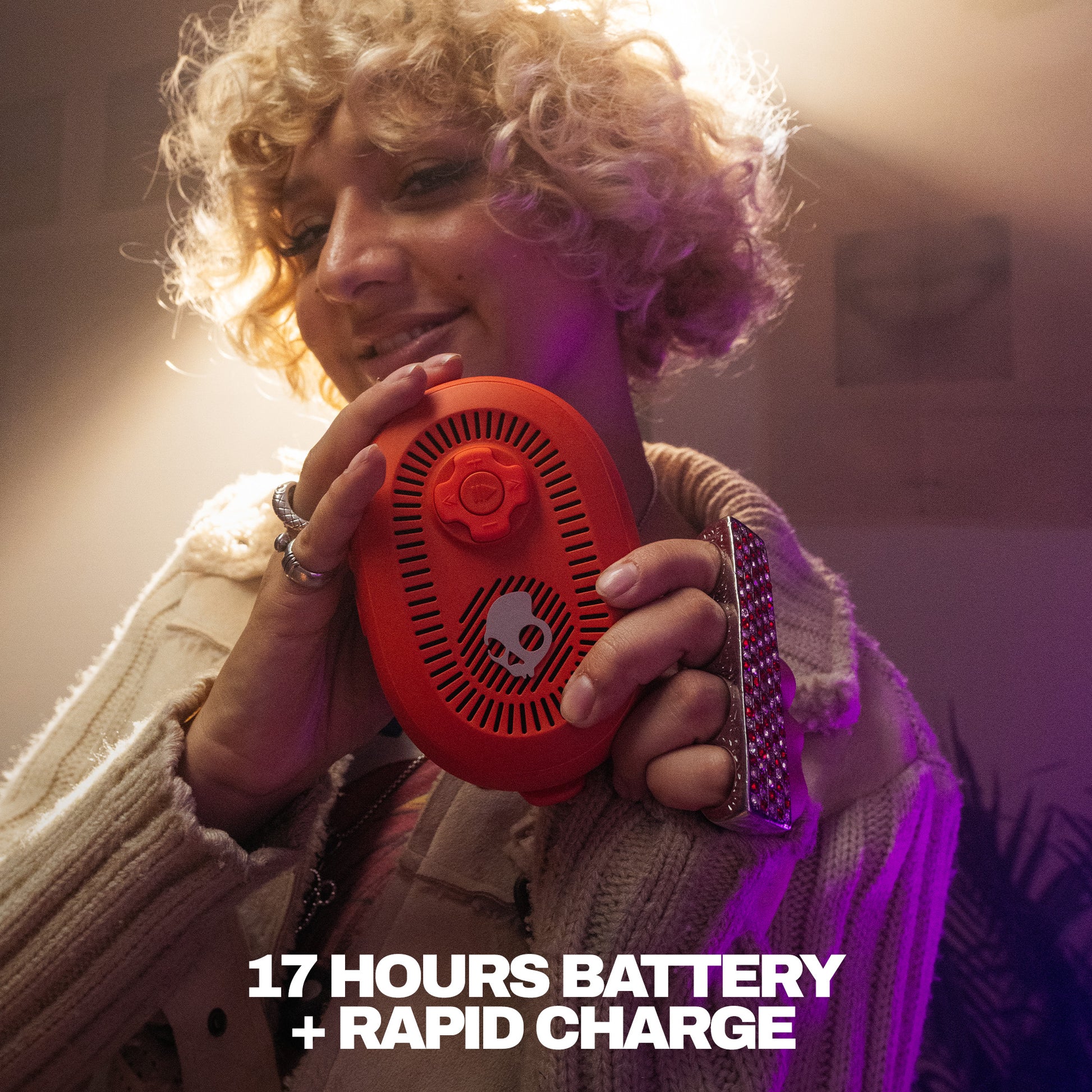 Person holding a red device with text about battery life and charging speed. | Plasma