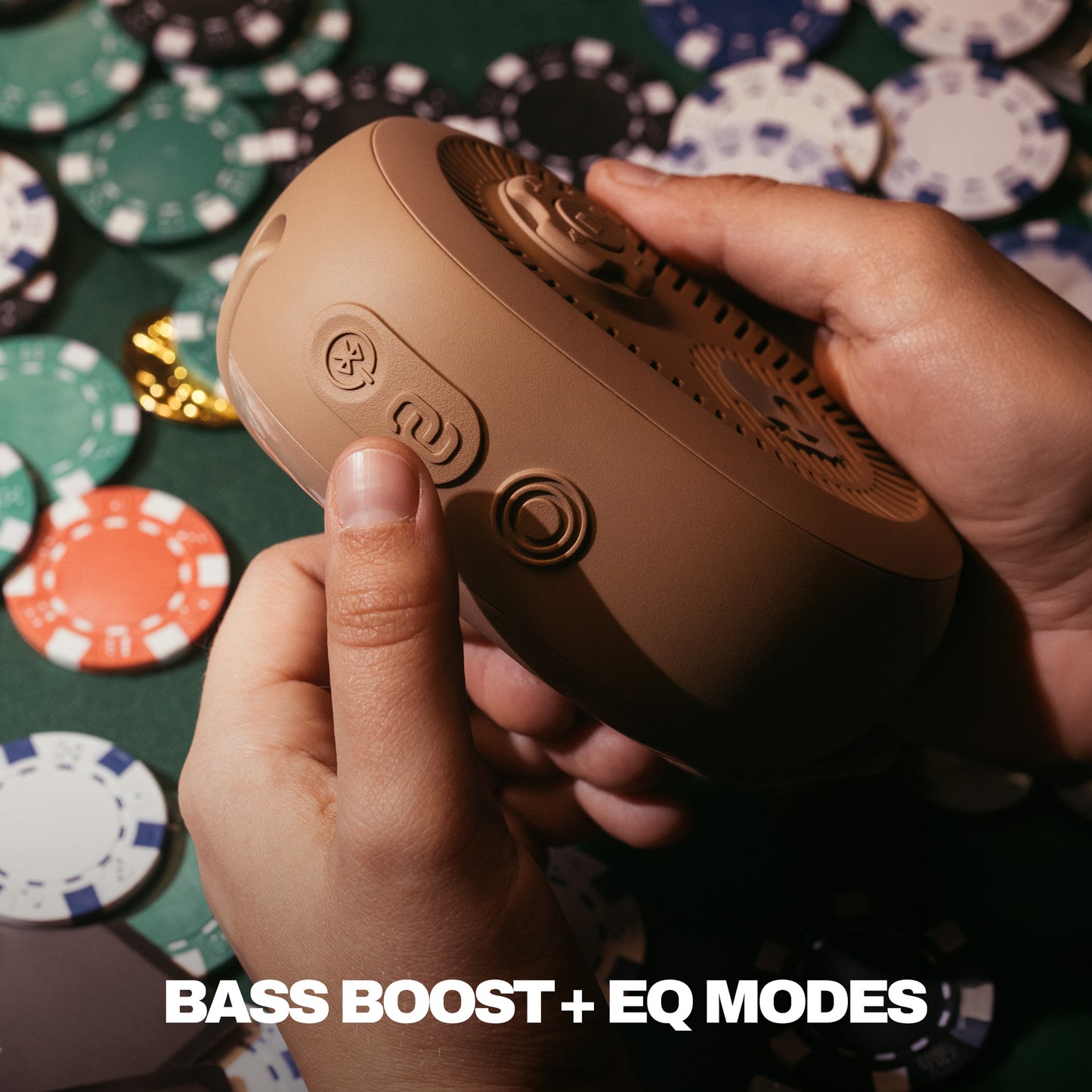 Hand holding a brown audio device with poker chips in the background | Primer