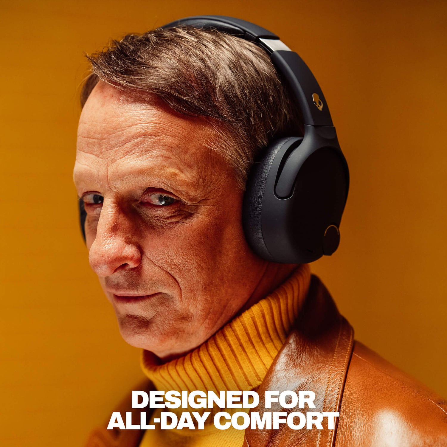 Tony Hawk wearing Crusher 720 over-ear headphones with an orange background with title 'Designed for All-Day Comfort" | True Black